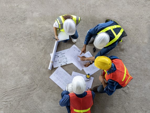 Kolleger på en byggeplass ser på arbeidstegninger sammen.